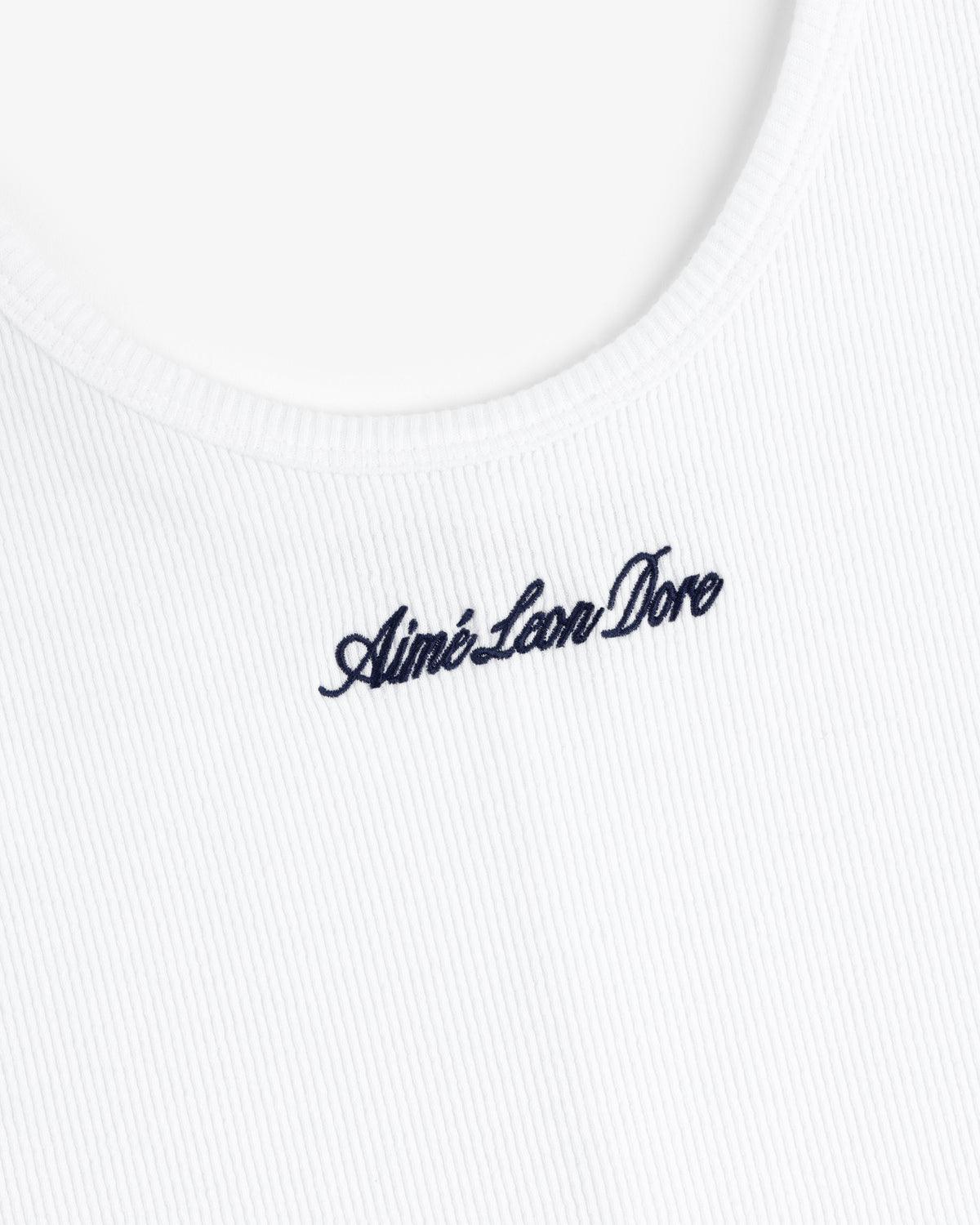 Close-up of a white ribbed Embroidered Logo Tank Dress with navy blue Aimé Leon Dore script near the neckline.
