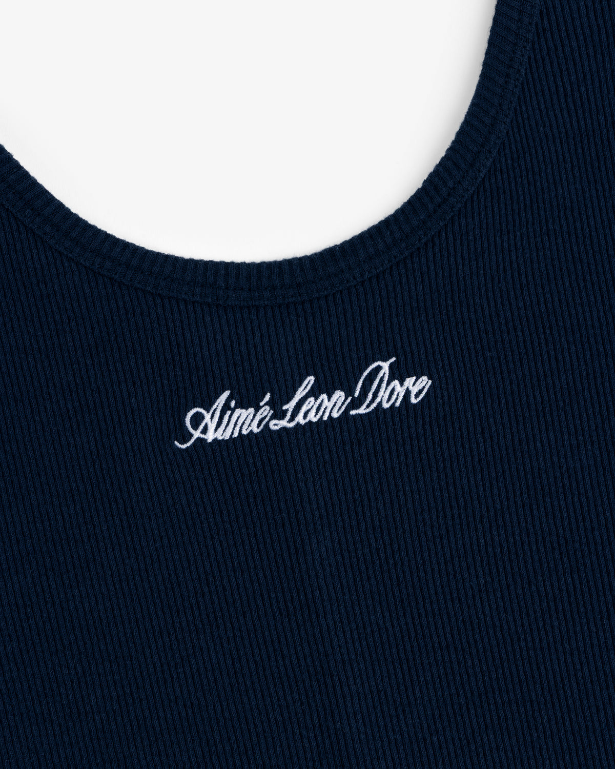 Close-up of a navy ribbed Embroidered Logo Tank Dress with white cursive Aimé Leon Dore near the neckline.