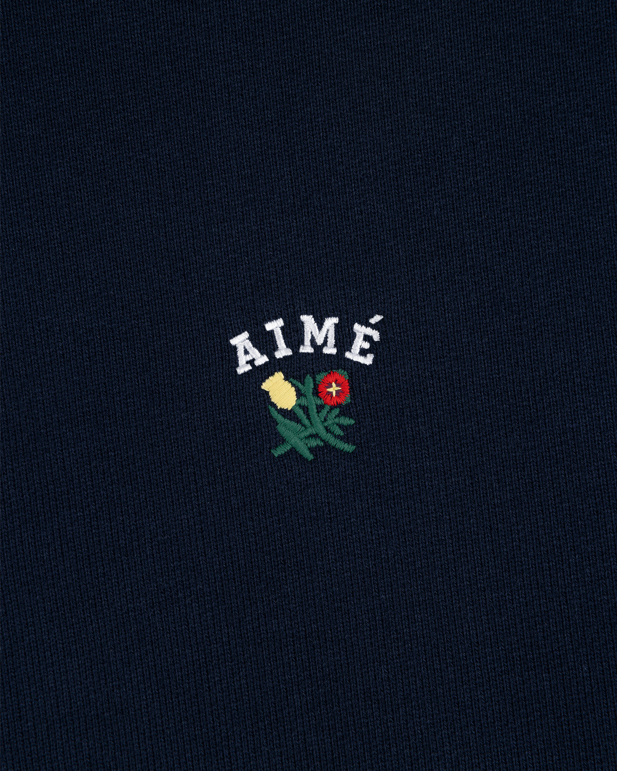 Navy Crest Hoodie featuring AIMÉ in white above yellow and red embroidered flowers with green leaves.