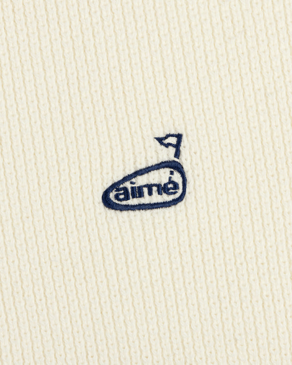 The ALD Golf Piqué Full Zip Sweater features white ribbed fabric and a small blue embroidered aimé logo with an arrow above the "e".