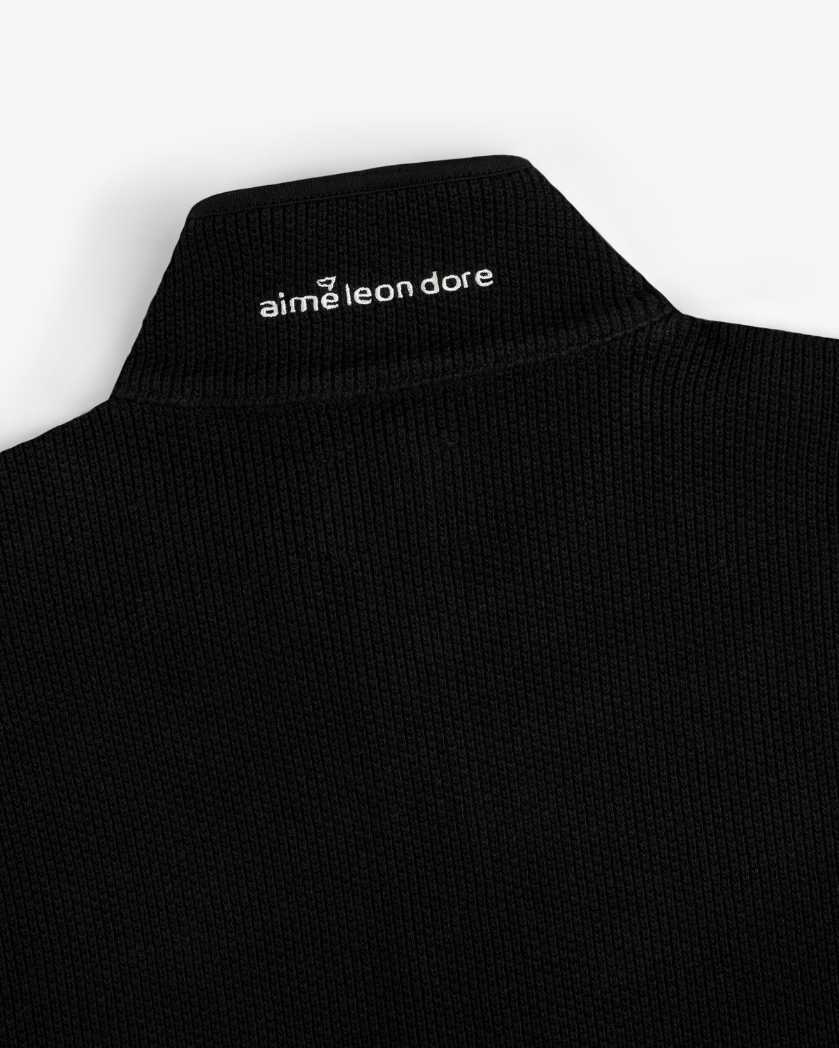 Black ribbed ALD Golf Piqué Full Zip Sweater with white logo and emblem on back of collar.