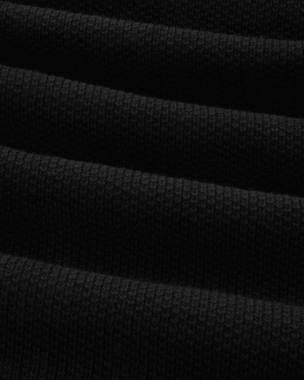 Close-up of the ALD Golf Piqué Full Zip Sweater's folded black ribbed fabric with visible textured lines.