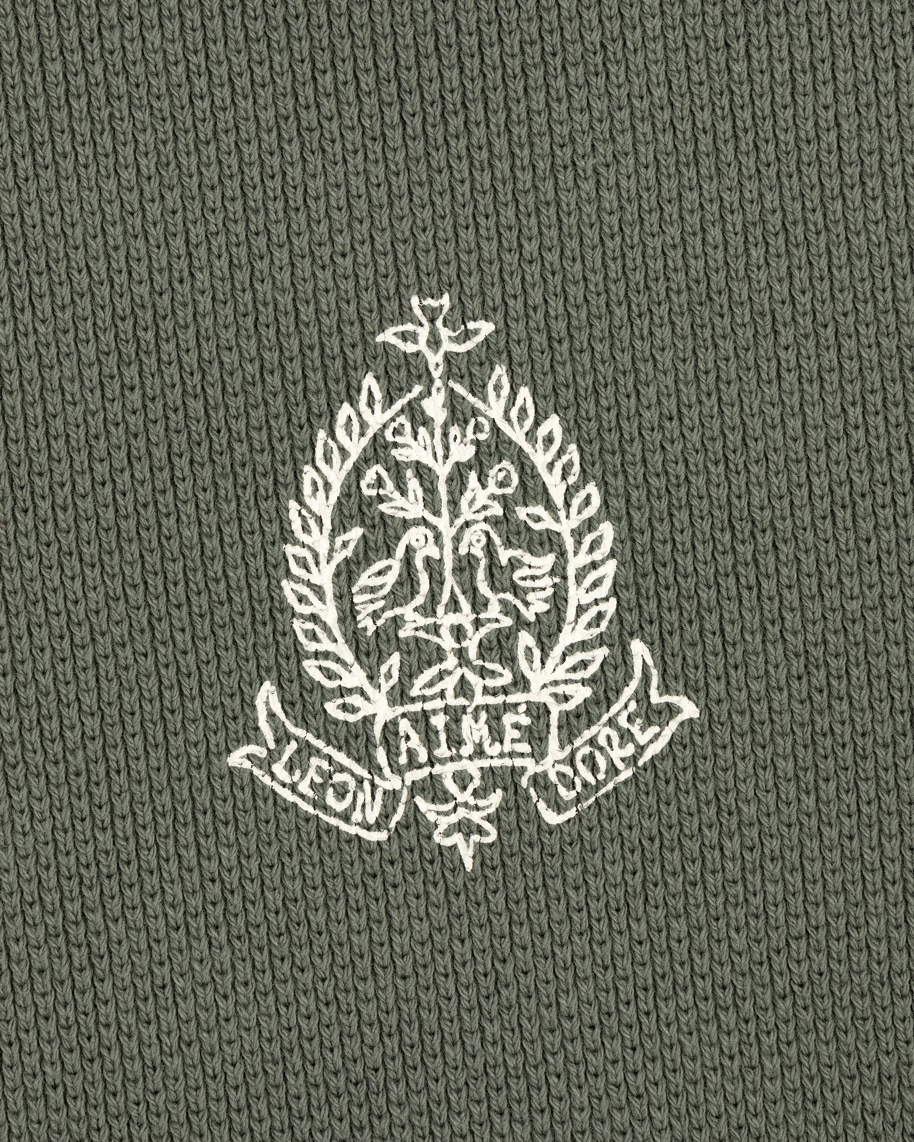Embroidered white crest with birds, leaves, and AIME LEON DORE text on olive Saint George Piqué Crewneck Sweatshirt.