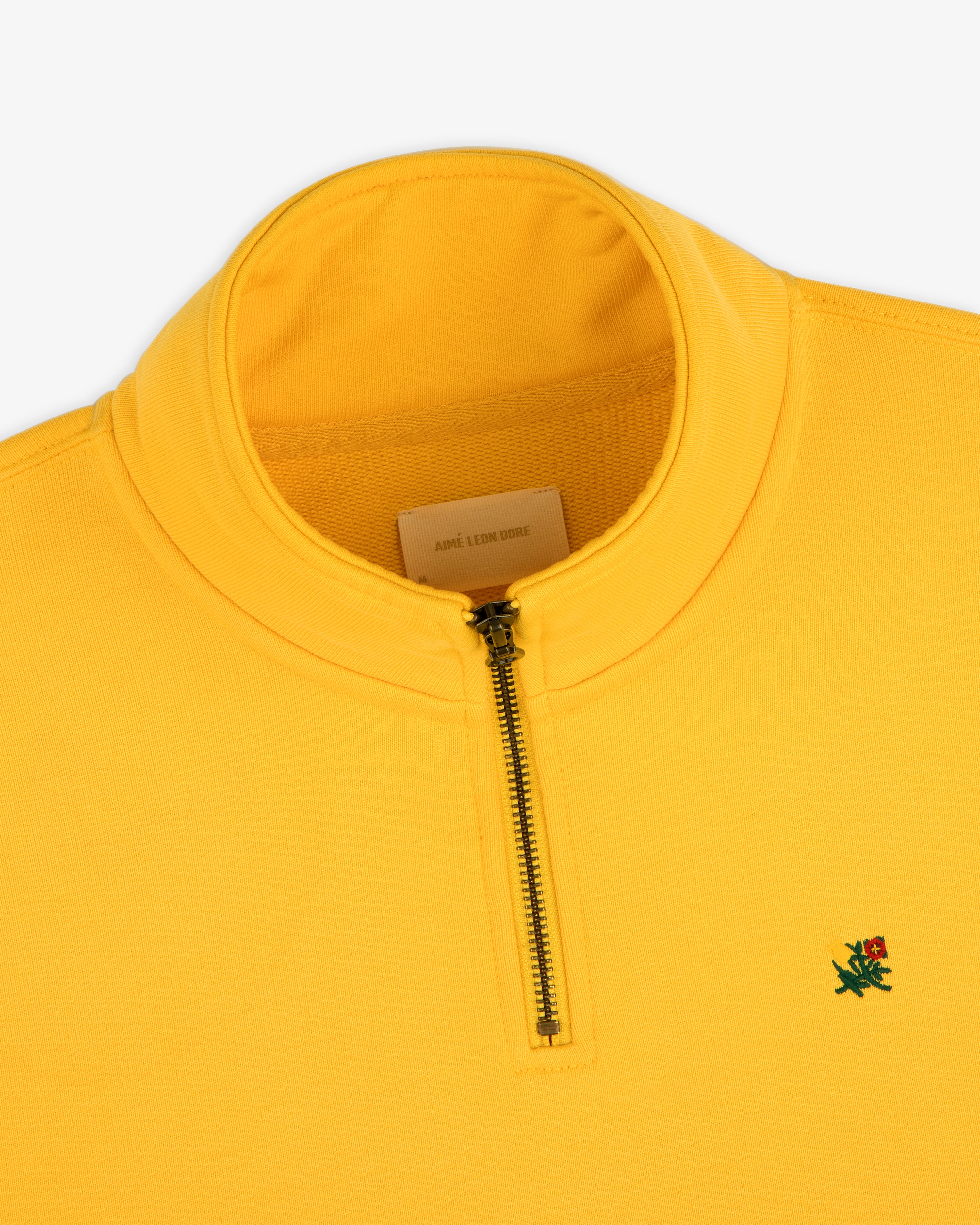 Sun Faded Crest Quarter Zip: Yellow pullover with standing collar, green and red embroidered logo on the chest.