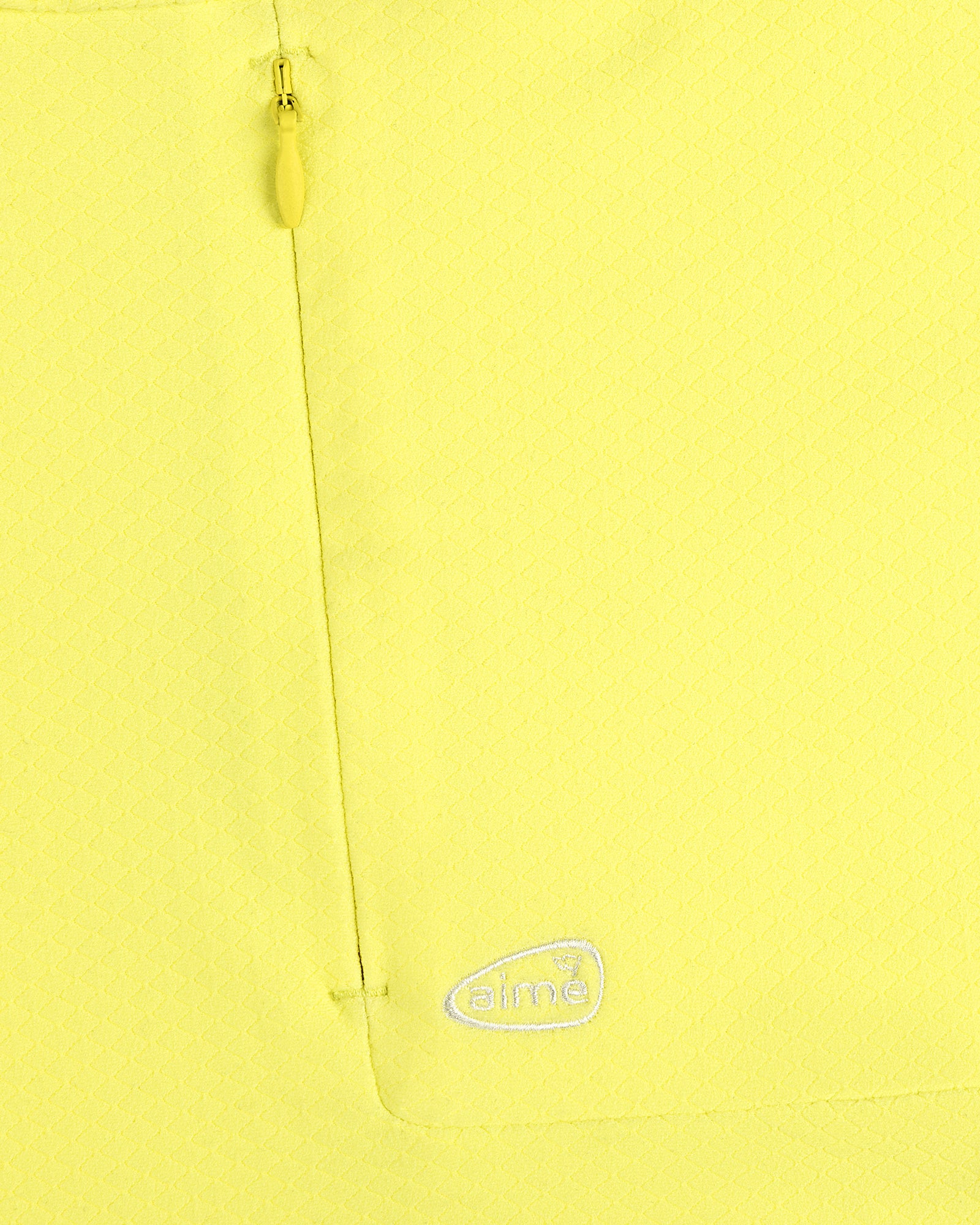 Close-up of ALD Golf Quarter Zip Pullover in yellow with textured fabric, zip pocket, and embroidered white aimé logo.