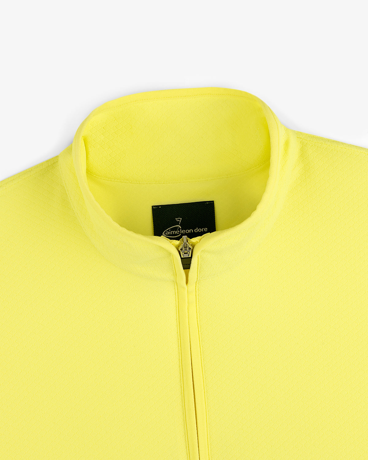 Close-up of the ALD Golf Quarter Zip Pullover in bright yellow with a stand collar and black label at the neckline.