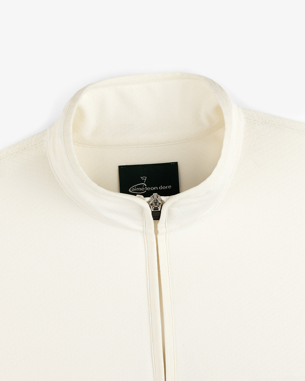 Close-up of a cream ALD Golf Quarter Zip Pullover with stand collar and visible Aimé Leon Dore label inside.