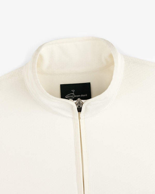Close-up of a cream ALD Golf Quarter Zip Pullover with stand collar and visible Aimé Leon Dore label inside.
