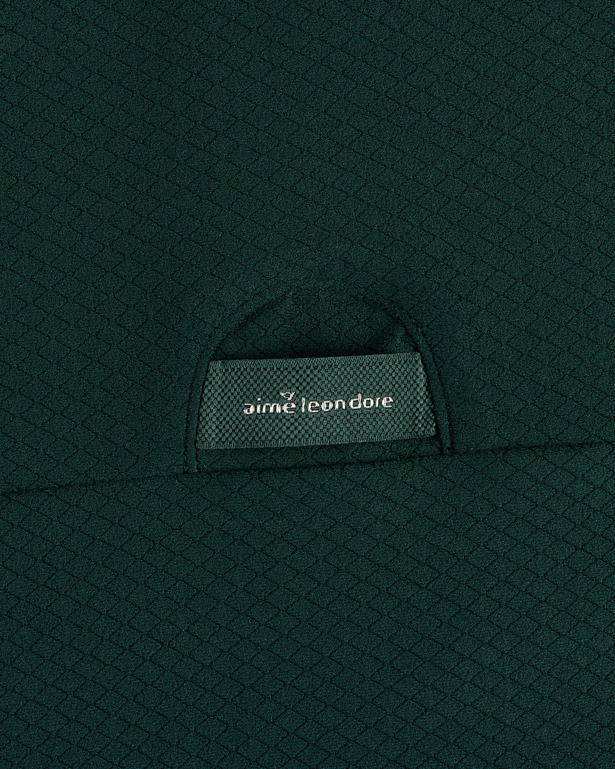 Close-up of textured dark green ALD Golf Quarter Zip Pullover with label partially visible in the pocket.