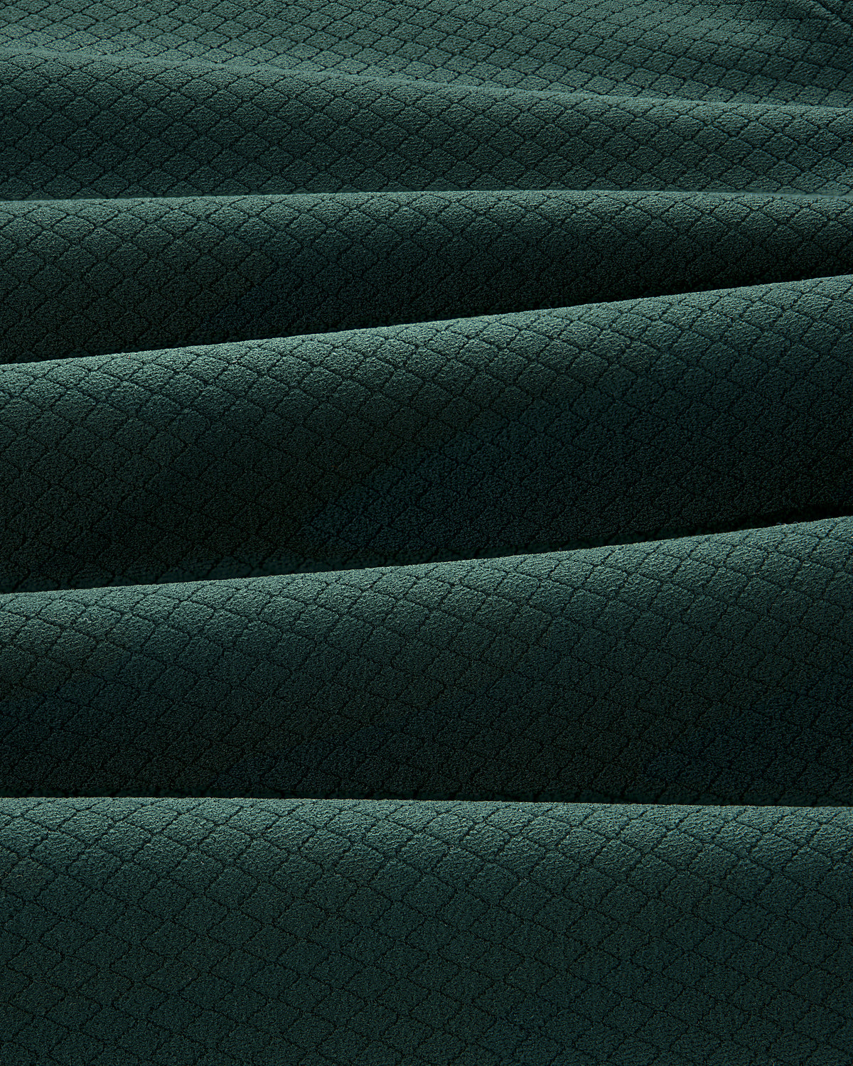 The ALD Golf Quarter Zip Pullover features dark green fabric with a subtle diamond pattern and soft horizontal pleats.