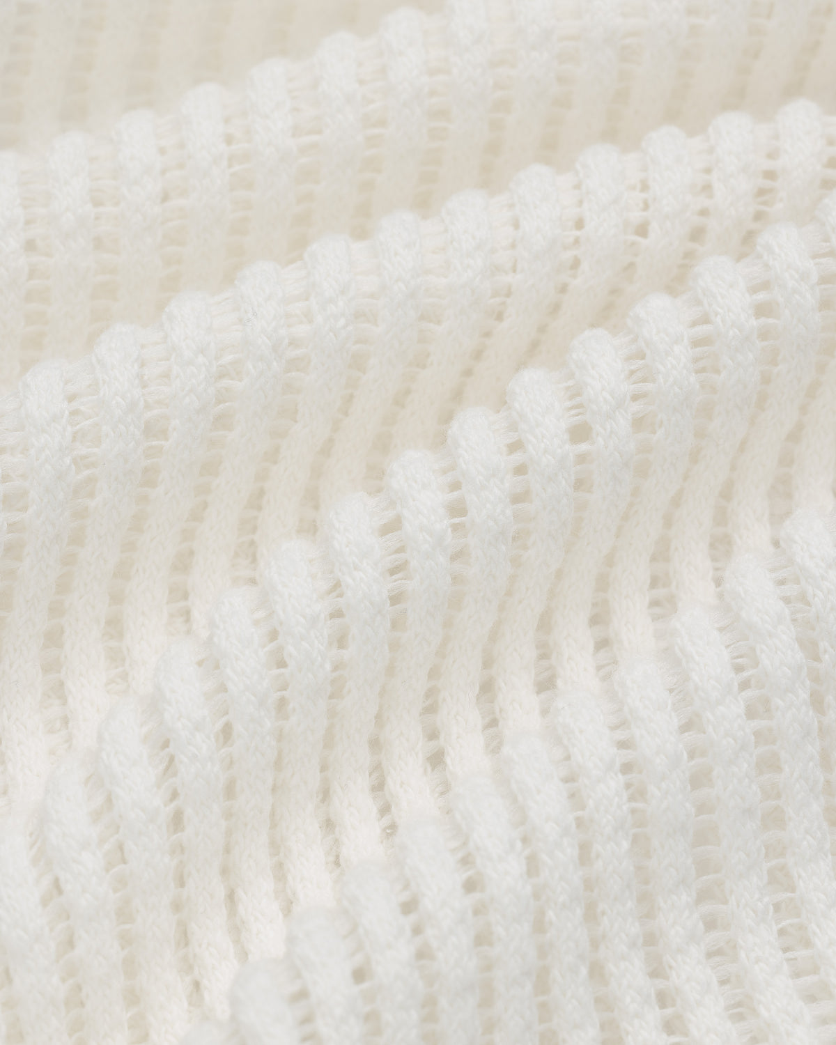 Close-up of Mesh V-Neck Tee in white, featuring ribbed knit texture with wavy horizontal ridges and soft material.
