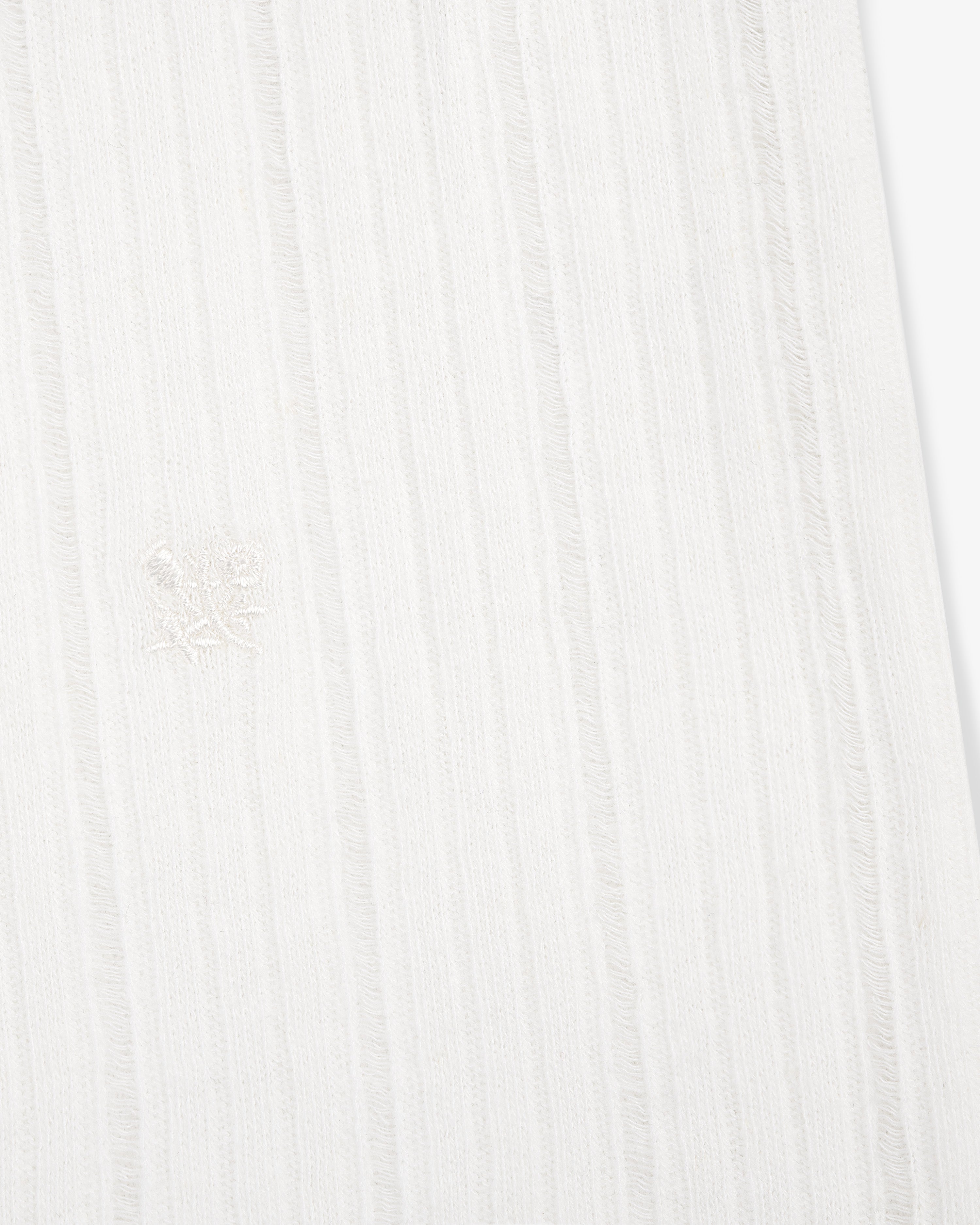 Close-up of the Drop Needle Tank Top's white ribbed fabric with subtle vertical stripes and a central embroidered emblem.