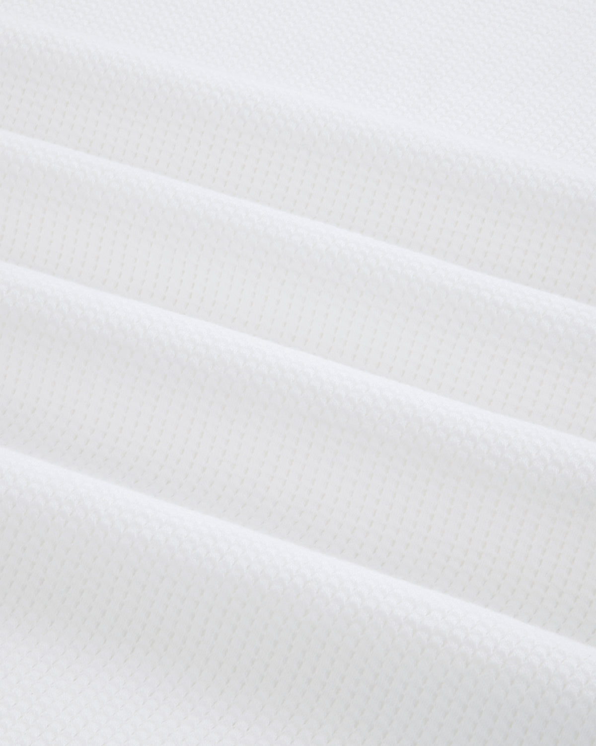 Close-up of folded white Mesh Muscle Tank fabric with a subtle geometric pattern and soft, even lighting.