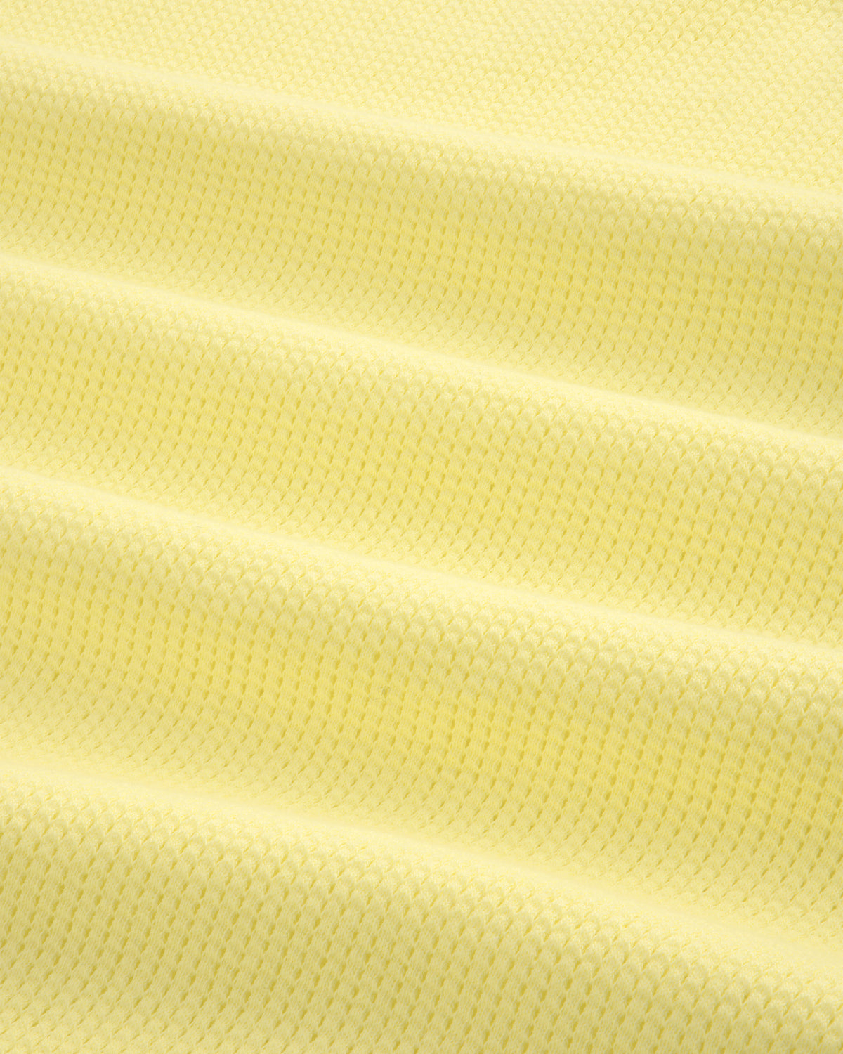 Close-up of the Mesh Muscle Tank in light yellow, showing its textured fabric and subtle horizontal folds.