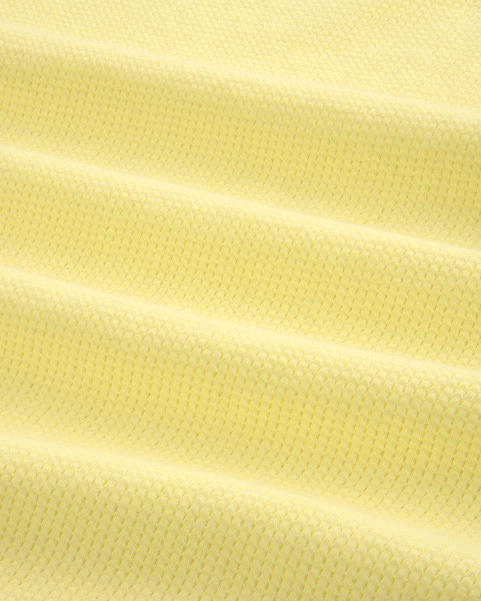 Close-up of the Mesh Muscle Tank in light yellow, showing its textured fabric and subtle horizontal folds.