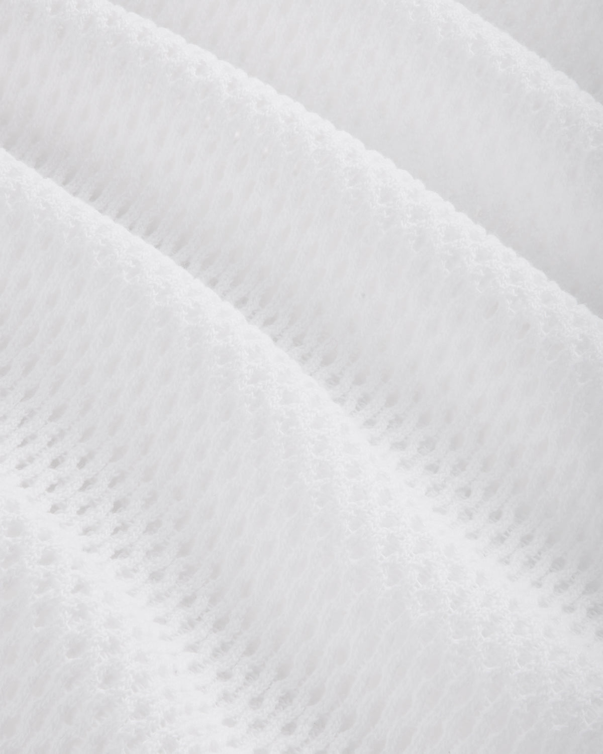 Close-up of the Mesh Tank Top's white textured fabric featuring a soft, quilted, diagonal wavy pattern.