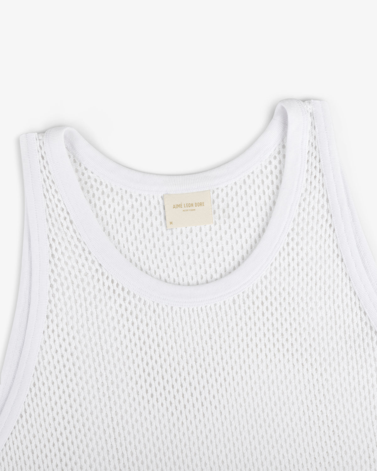Close-up of Mesh Tank Top in white with ribbed edges and a beige neck label, shown on a white background.