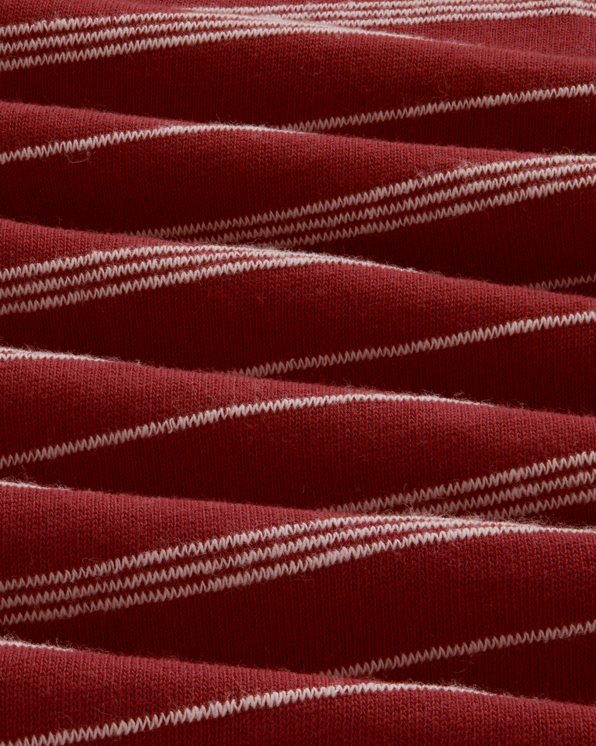 Close-up of Jacquard Striped Rollneck Tee in red with white horizontal stripes and wavy, textured fabric folds.