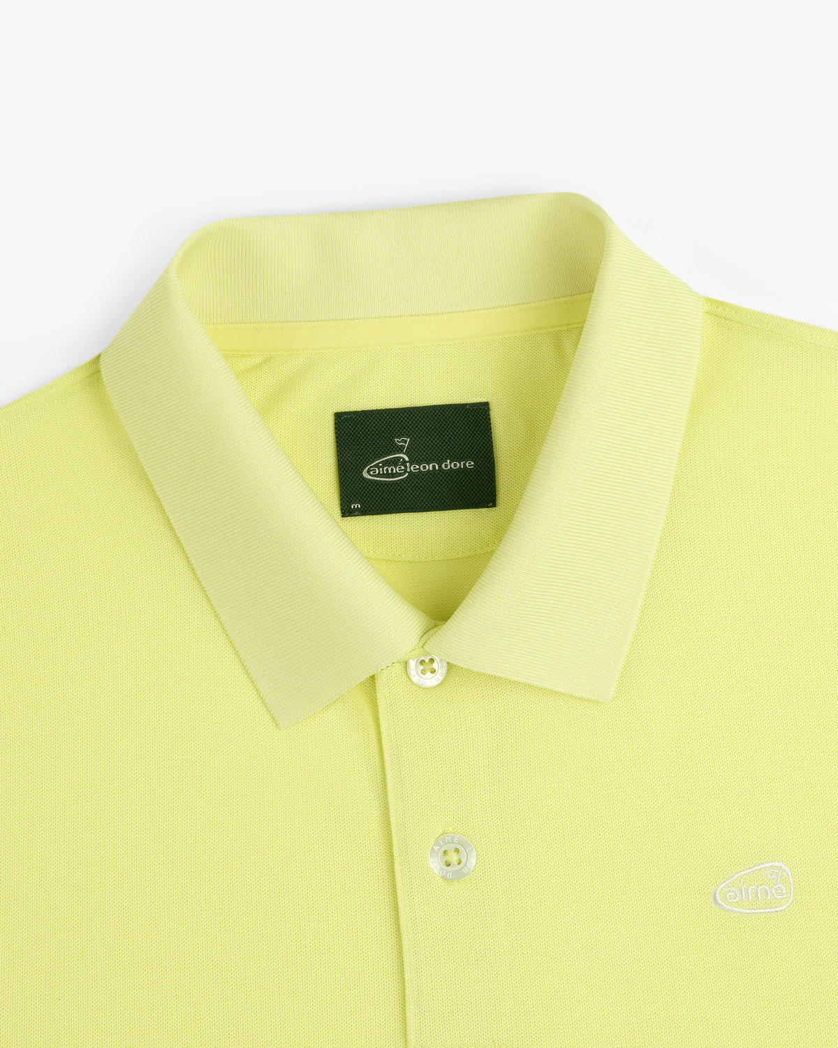 ALD Golf Polo: Yellow collared shirt with buttons, green neck label, and small embroidered logo.