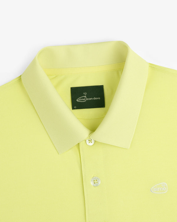 ALD Golf Polo: Yellow collared shirt with buttons, green neck label, and small embroidered logo.