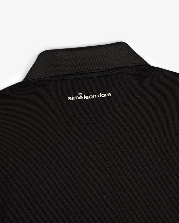 Close-up of an ALD Golf Polo’s black collar with aime leon dore text printed in white below the back neckline.