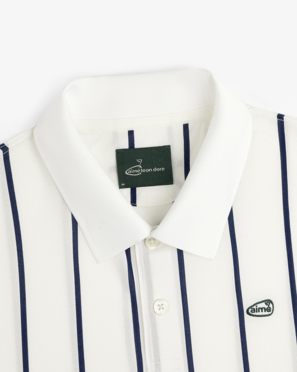 ALD Golf Polo: white collared shirt with navy stripes and "aimé" logo patch on the chest.