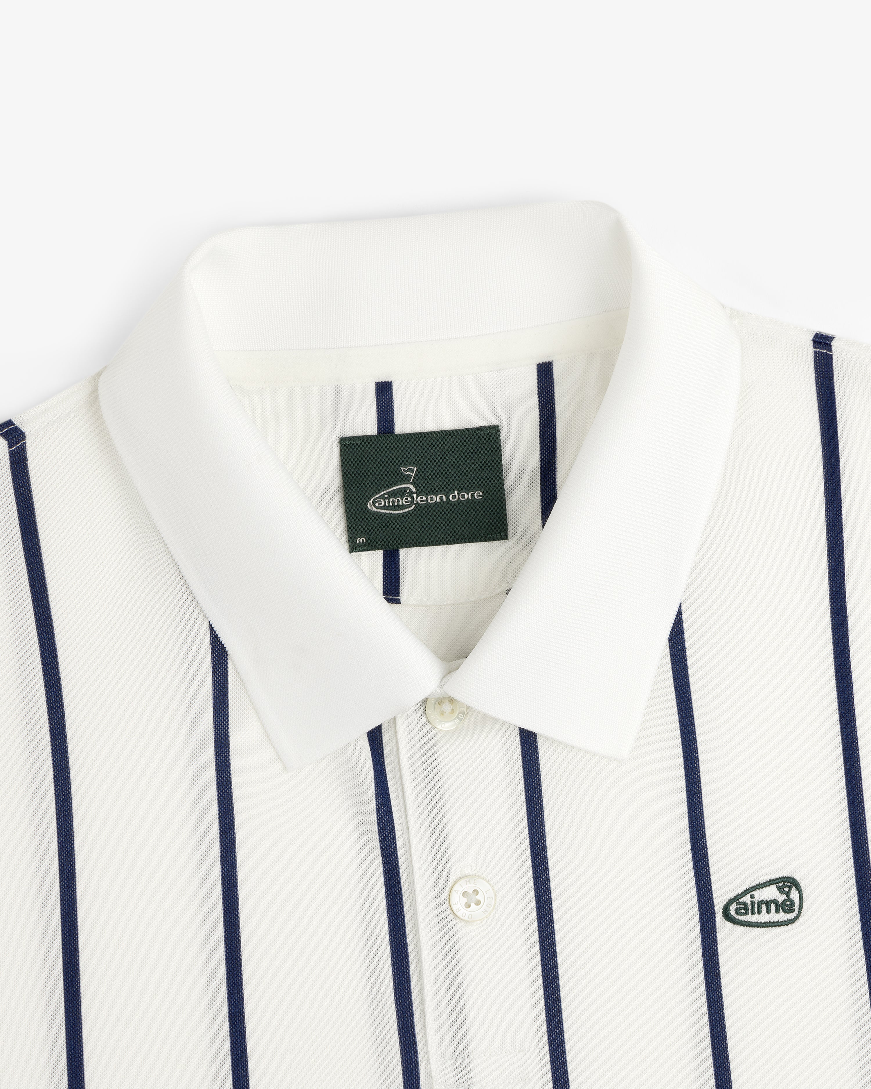 ALD Golf Polo: white collared shirt with navy stripes and "aimé" logo patch on the chest.