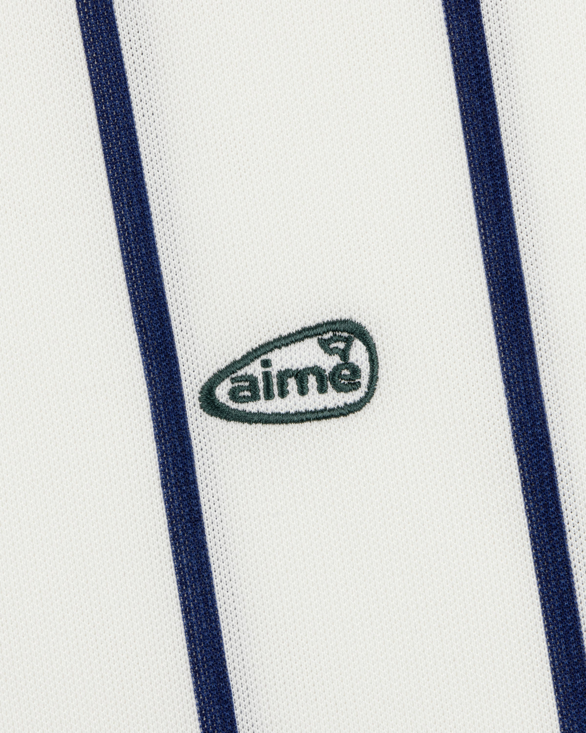 The ALD Golf Polo features white fabric with vertical navy stripes and a small green aimé logo embroidered at the center.