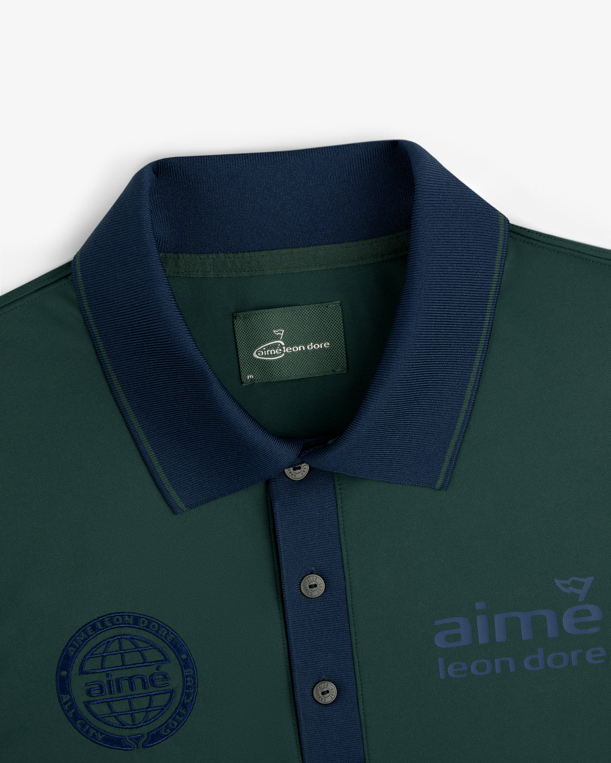 ALD Golf Tour Polo in dark green with navy collar, buttons, and "aime leon dore" branding on chest and label.
