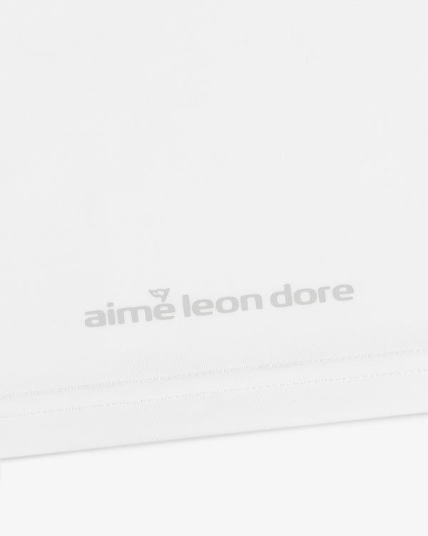 Close-up of a white ALD Golf Performance Tee with the aime leon dore logo in light gray near the bottom hem.