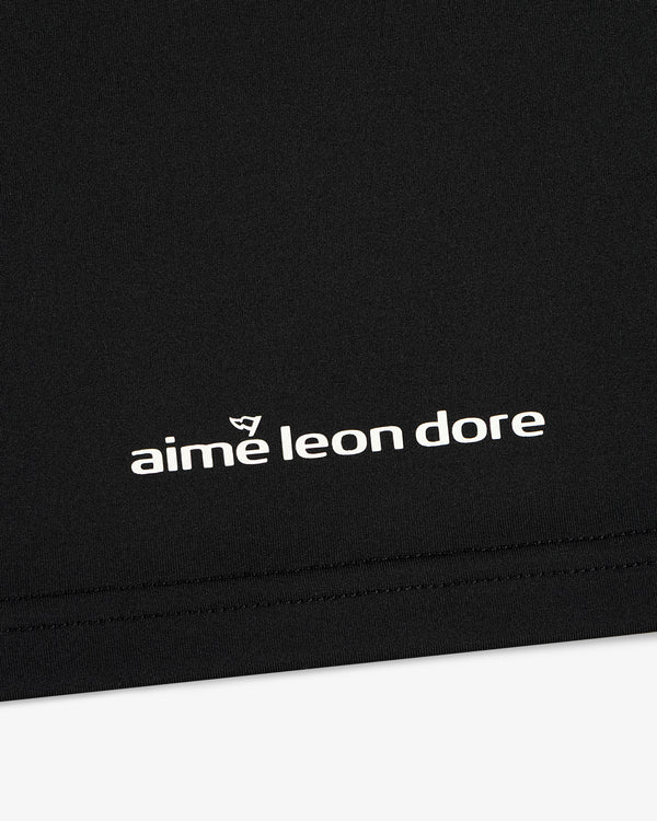 Close-up of black ALD Golf Performance Tee with white aime leon dore logo and stitching near the bottom edge.