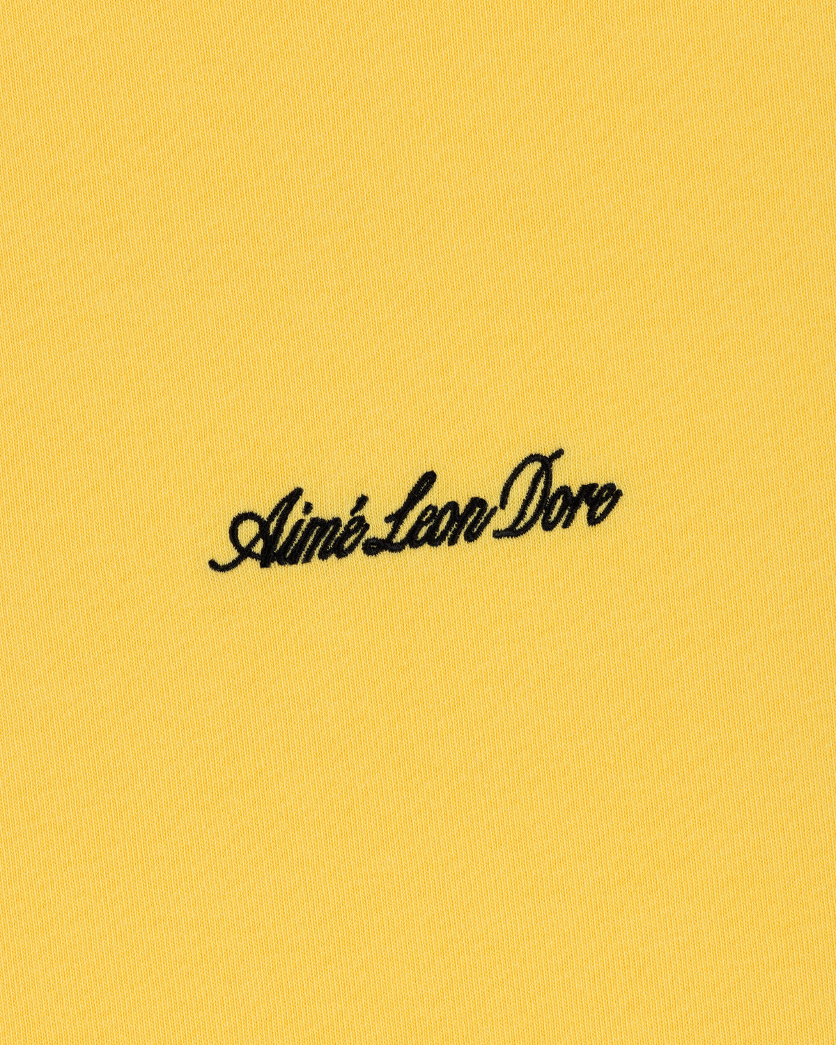 Black Aimé Leon Dore script logo embroidered on yellow Embroidered Logo Tee.