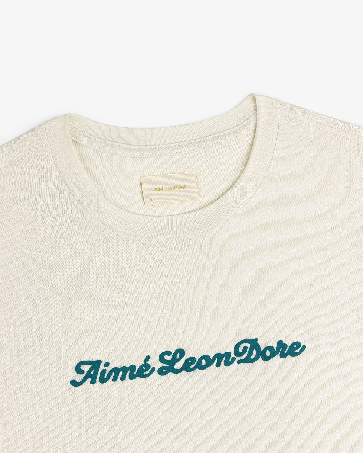 Cream Puff Print Slub Logo Tee with Aimé Leon Dore in green script across the chest.