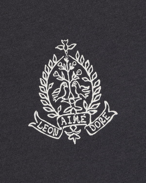 White embroidery of two birds, leafy branches, and "LEON AIME DOPE" on the Saint George Graphic Tee.