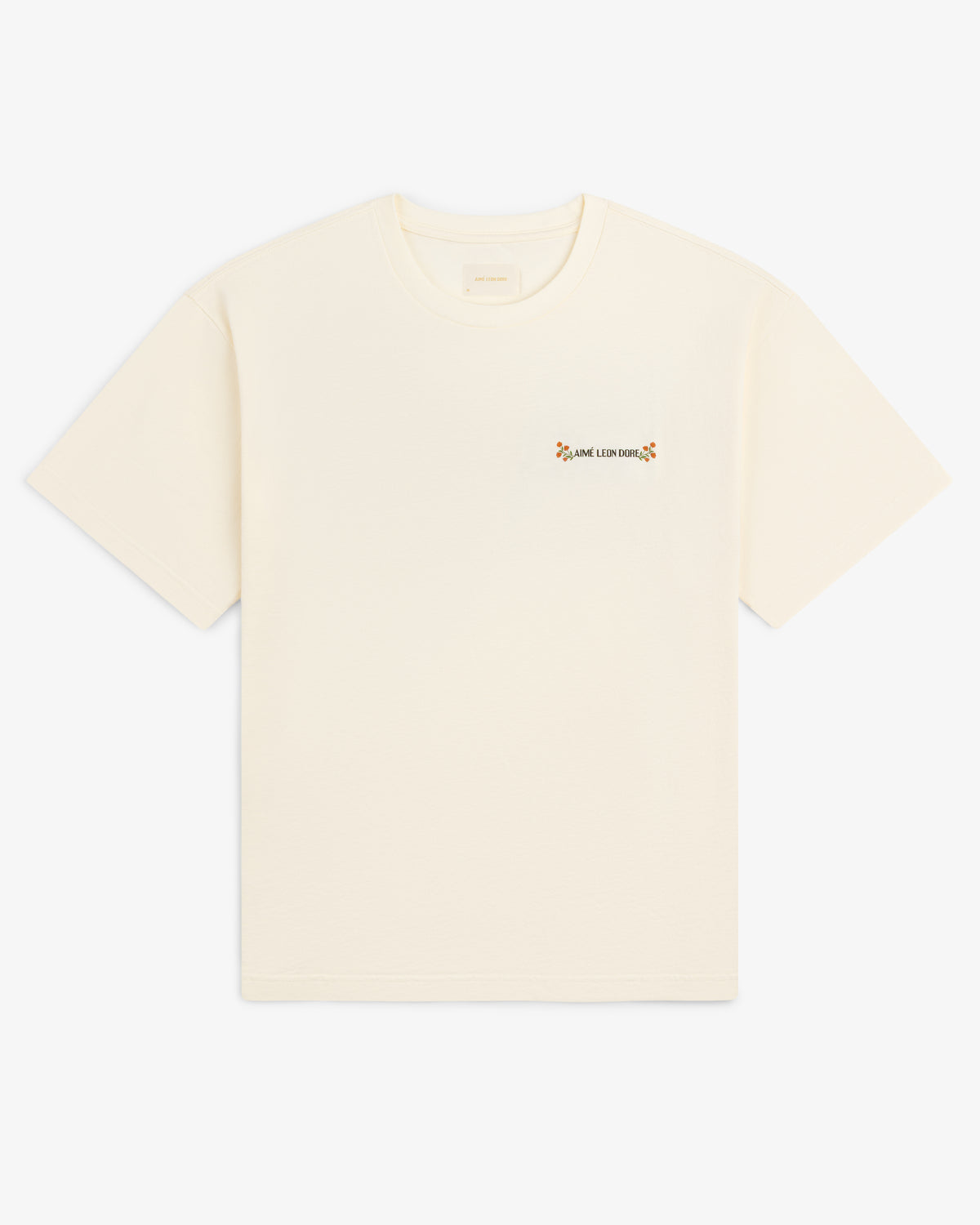 Aimé Postcard Tee: off-white short-sleeve shirt with small floral graphic and text on the left chest.