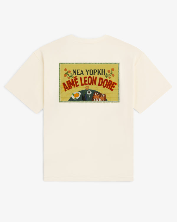 Aimé Postcard Tee in cream features a colorful rectangle graphic and NEA YOPKH AIME LEON DORE text on the back.