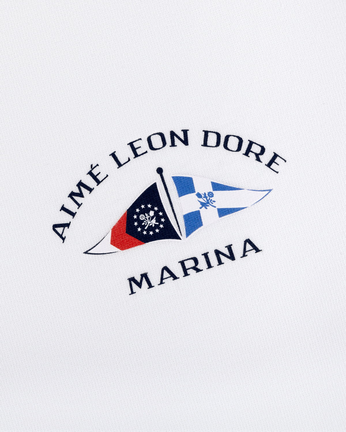 Marina Tee featuring embroidered Aimé Leon Dore Marina logo with two nautical flags on a white background.