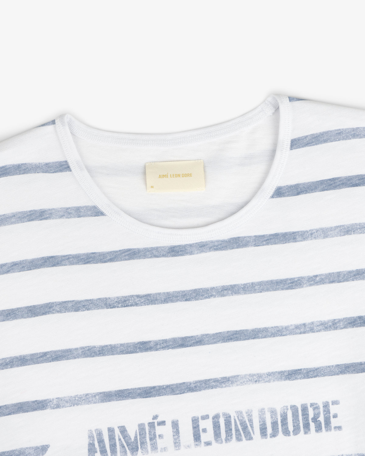 Slub Beach Tee: White tee with faded blue horizontal stripes and visible AIMÉ LEON DORE label inside the collar.