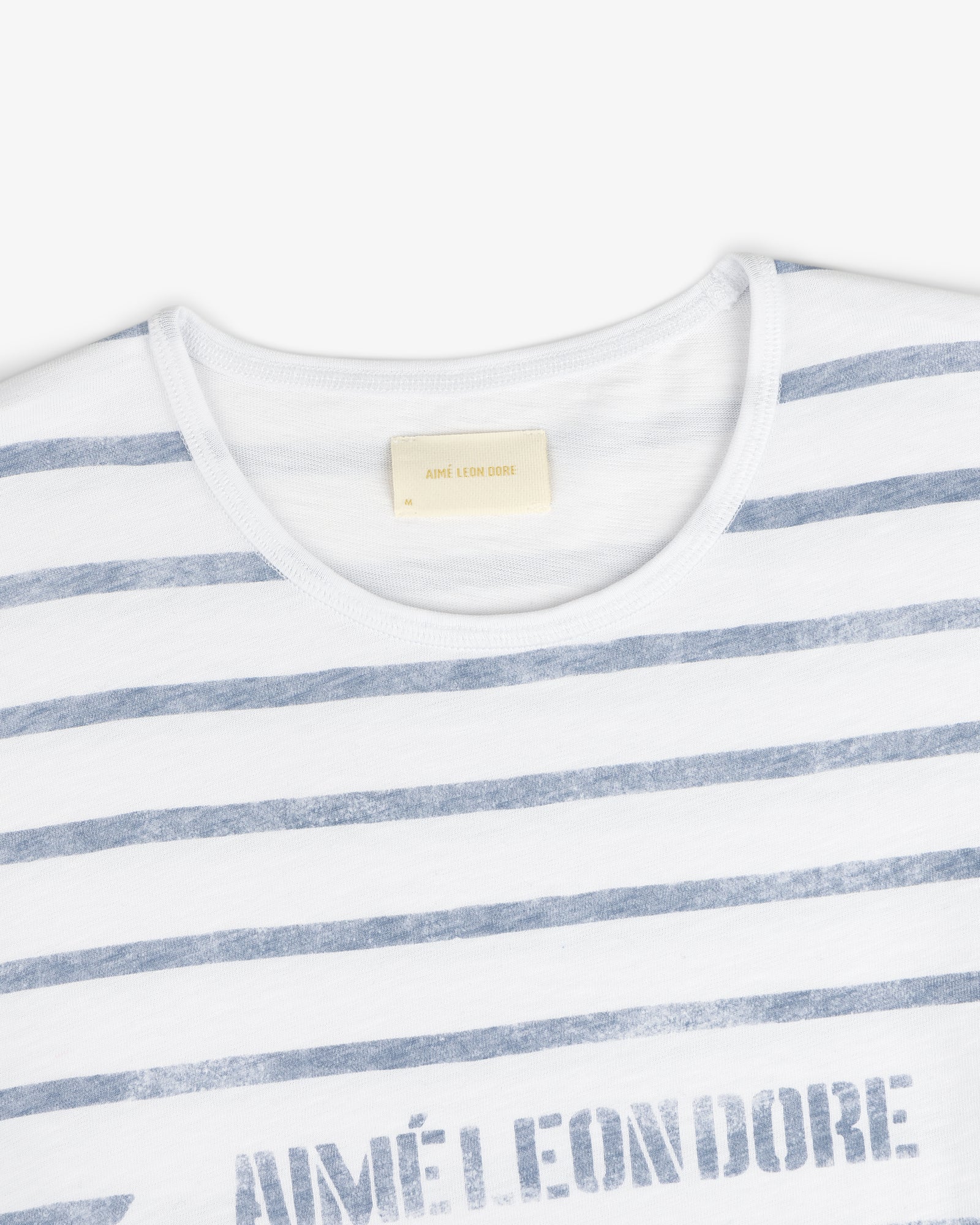 Slub Beach Tee: White tee with faded blue horizontal stripes and visible AIMÉ LEON DORE label inside the collar.