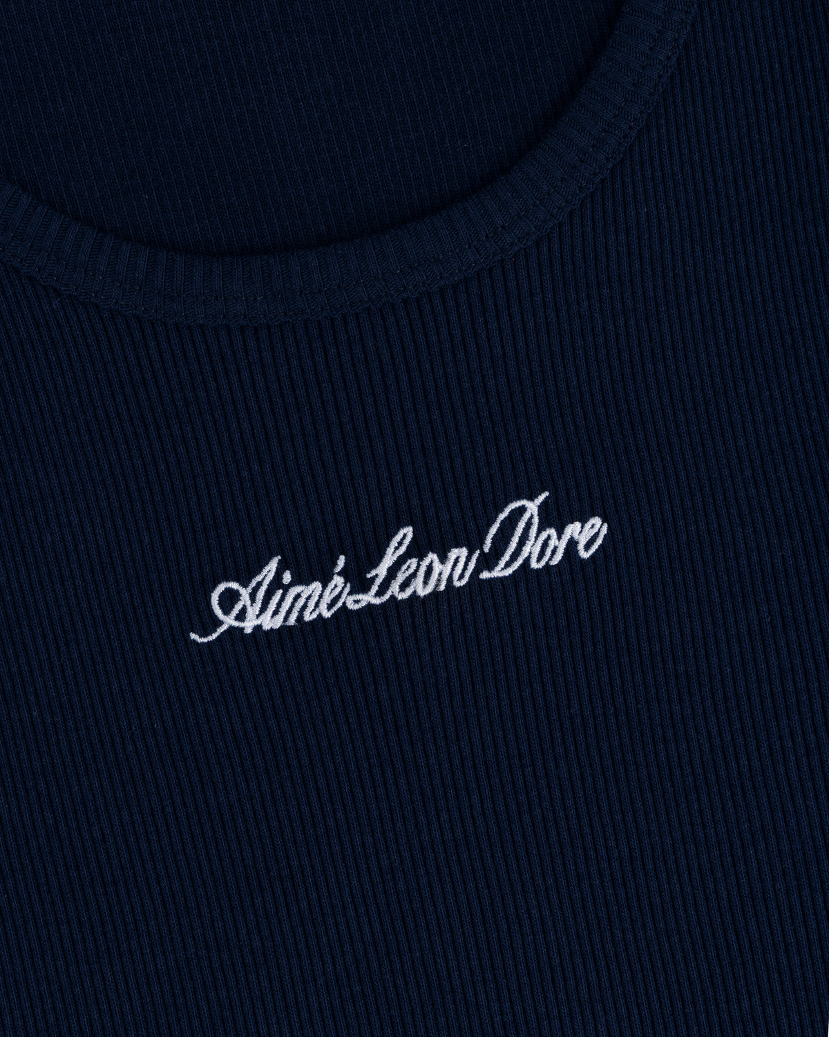Close-up of navy ribbed fabric on the Embroidered Logo Tank Top with Aimé Leon Dore in white cursive.