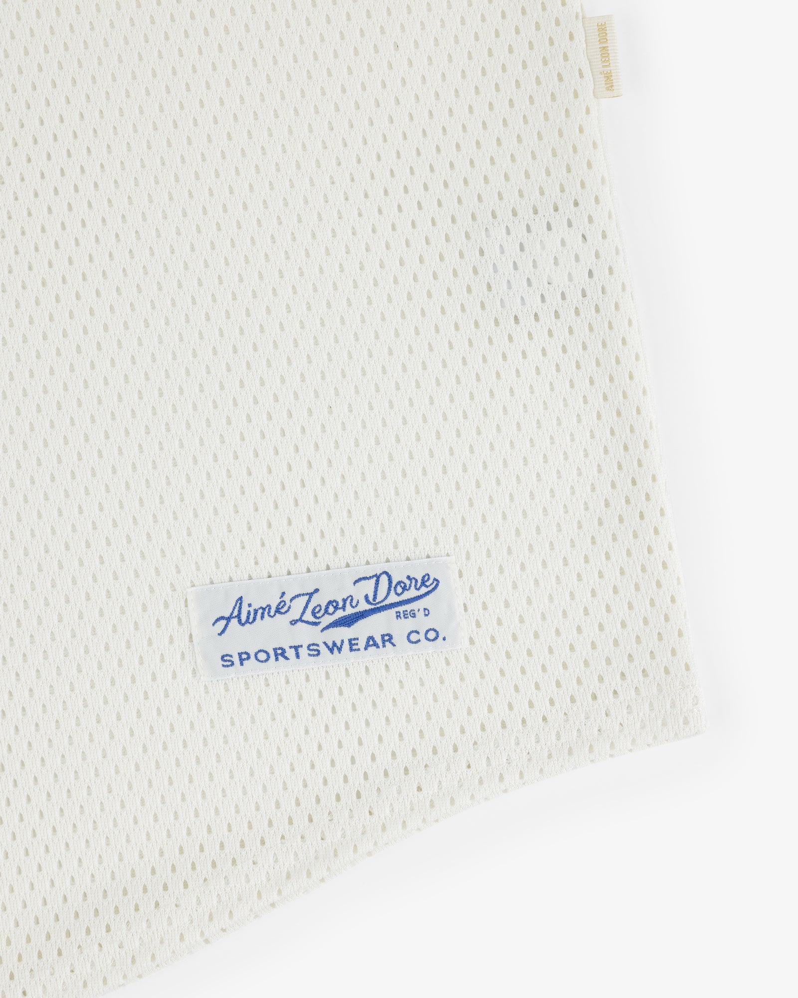 Close-up of white Mesh Batting Practice Jersey with a blue Aimé Leon Dore Sportswear Co. label on the corner.