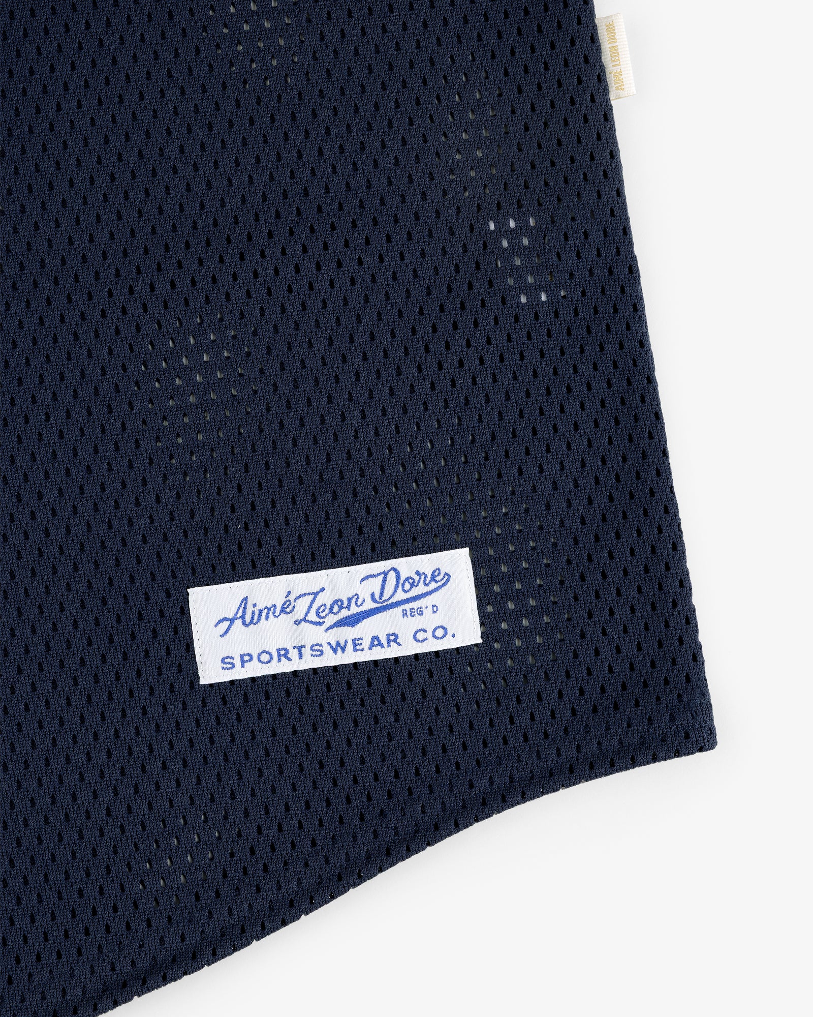 Close-up of navy blue Mesh Batting Practice Jersey with a white Aimé Leon Dore Sportswear Co. label sewn on.