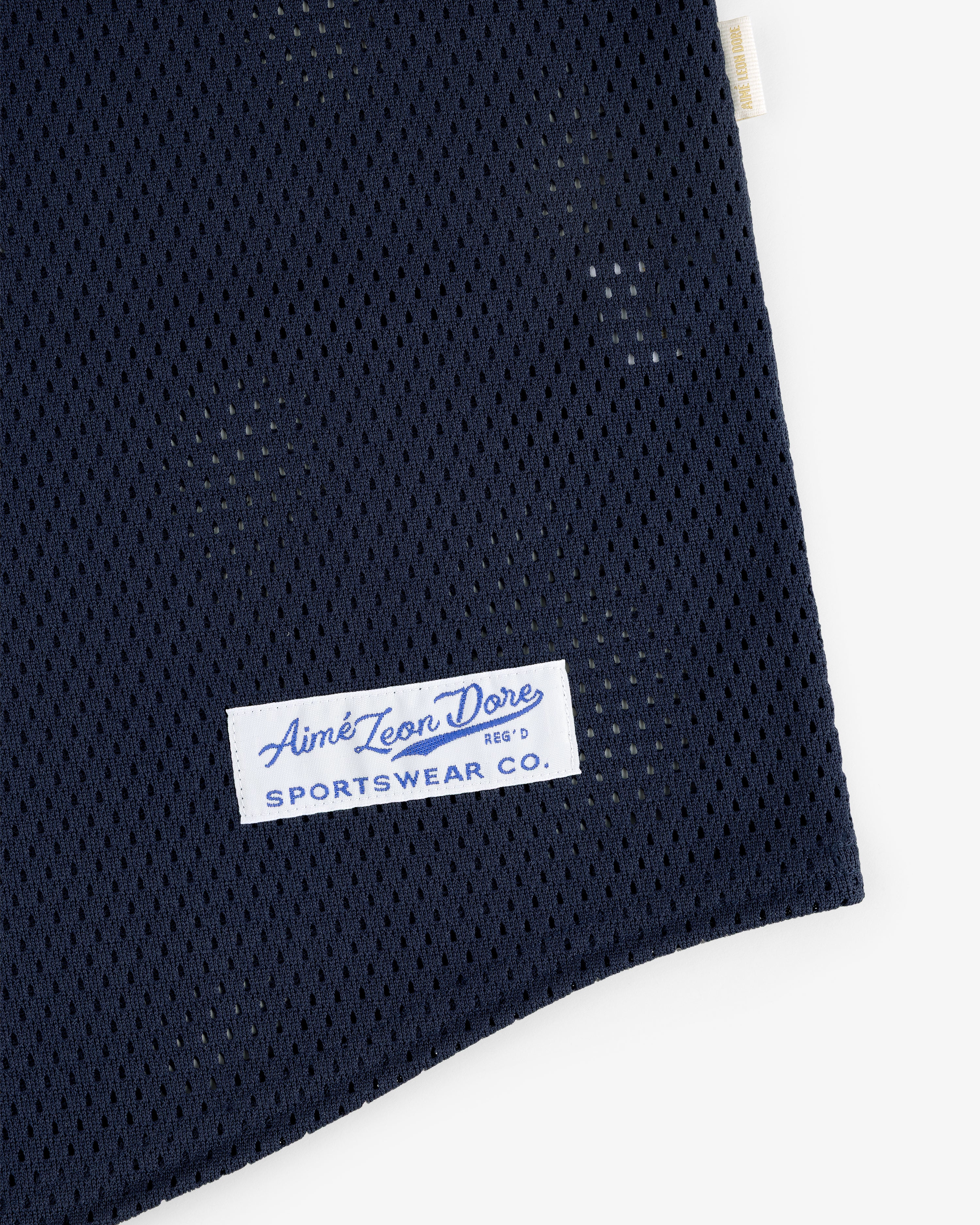 Close-up of navy blue Mesh Batting Practice Jersey with a white Aimé Leon Dore Sportswear Co. label sewn on.