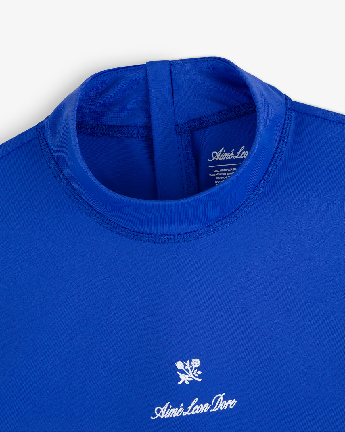 Close-up of the Short Sleeve Crest Rash Guard in royal blue with “Aimé Leon Dore” logo and white rose chest emblem.
