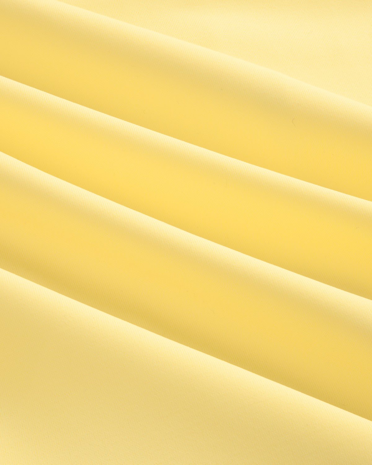 Close-up of smooth, light yellow Short Sleeve Crest Rash Guard fabric with soft, diagonal folds and gentle shadows.