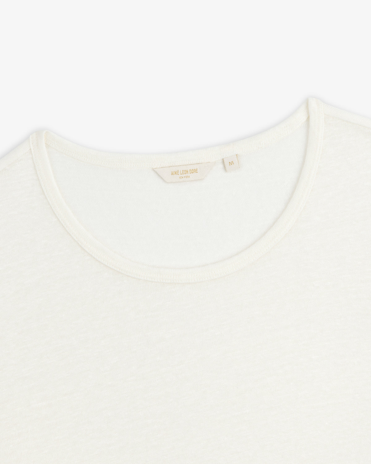 Close-up of the neckline of a plain white Linen Tee crew neck on a white background.