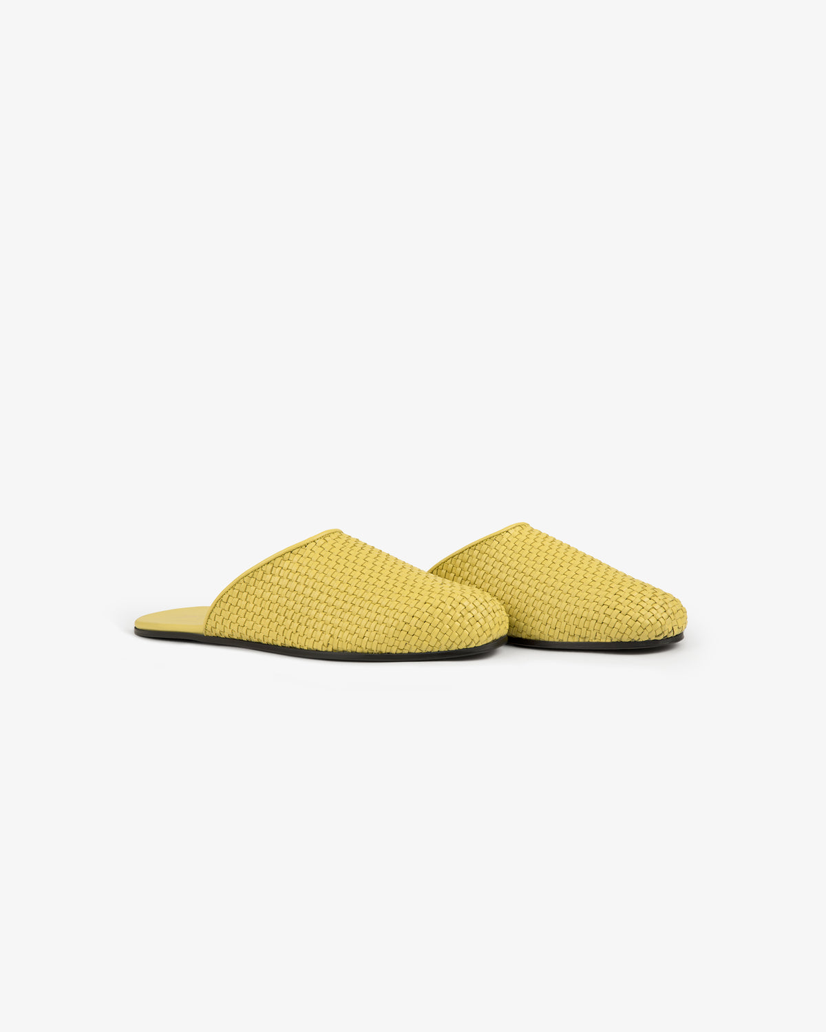 A pair of Leather Raffia Mule slippers in yellow with closed toes and black soles on a white background.