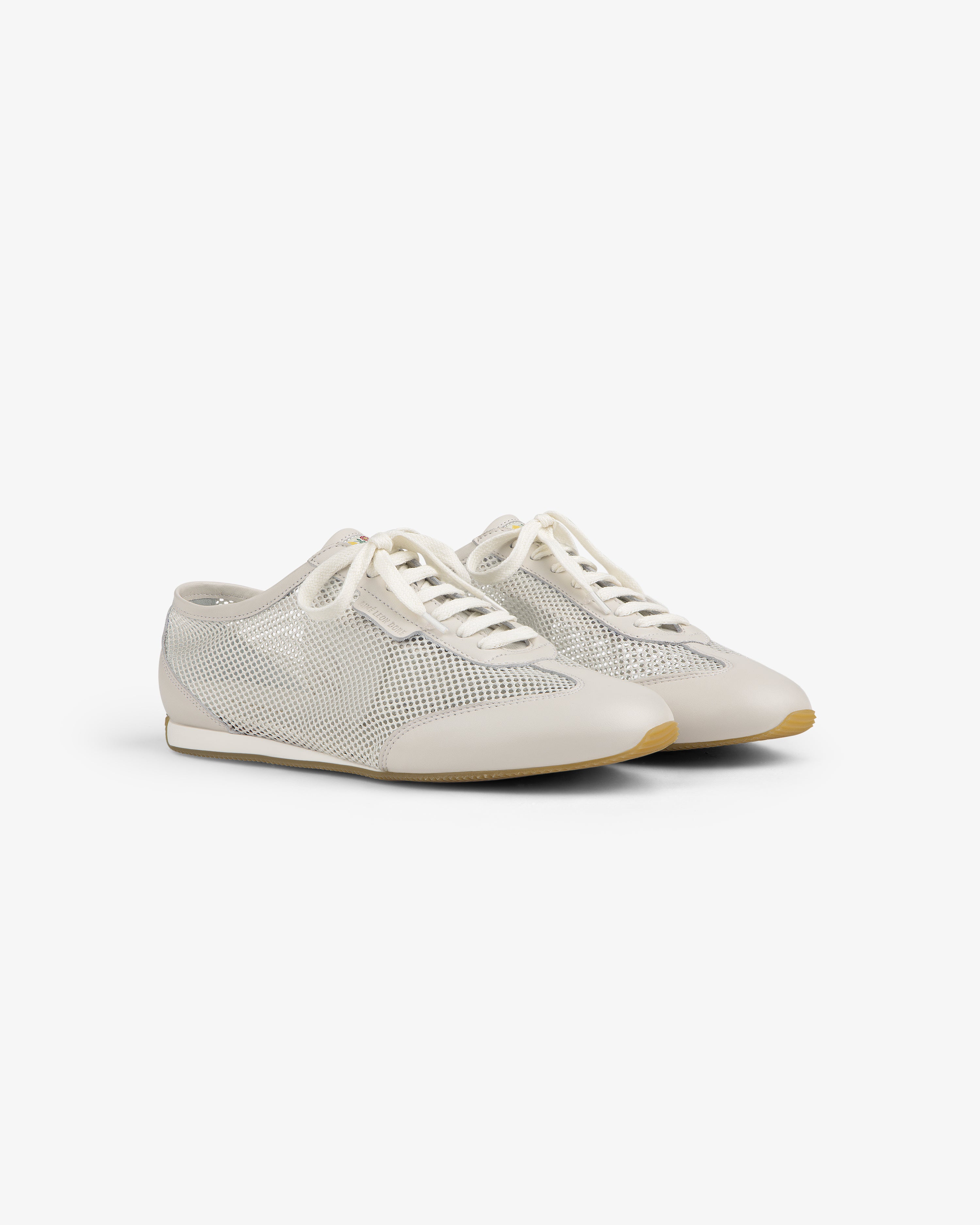 Low Profile Mesh Trainer: white mesh sneakers with lace-up fronts and beige soles, shown on a plain white background.