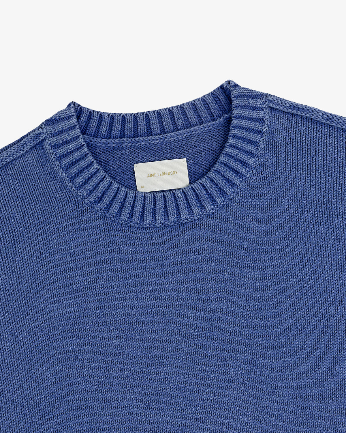 Washed Inside Out Sweater—blue knit crewneck with ribbed collar and white label inside neckline, on plain white background.