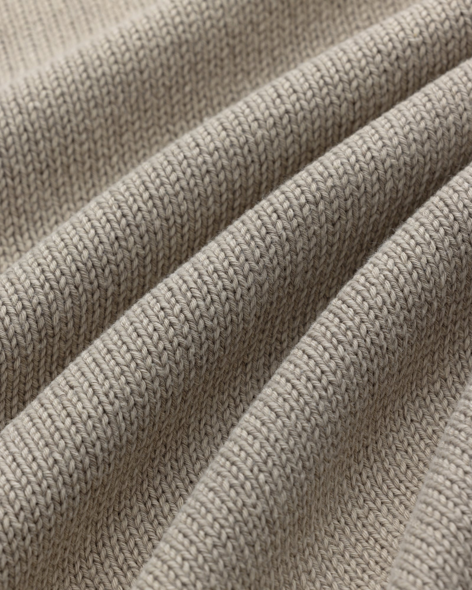 Close-up of Washed Inside Out Sweater in beige, showing textured knit stitches and gentle folds.